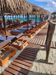 a row of chaise lounges and chairs on a beach at Aqua Mare Luxury Apartments in Paralia Katerinis