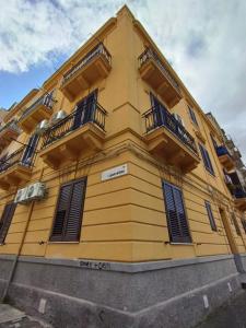 a yellow building with balconies on the side of it at Triscele house in Palermo