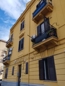 a yellow building with black windows and balconies at Triscele house in Palermo