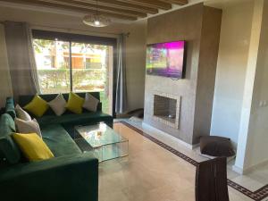 a living room with a green couch and a fireplace at Palmeraie dar dmana in Marrakesh