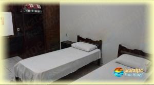 twee bedden in een kleine kamer met ermottermottermott bij Jacaraipe Praia Hotel in Serra