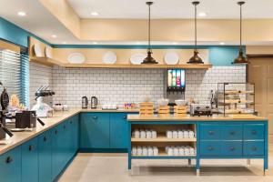 cocina con armarios azules y azulejos blancos en Country Inn & Suites by Radisson, Shreveport-Airport, LA en Shreveport