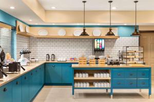 a kitchen with blue cabinets and white tiles at Country Inn & Suites by Radisson, Shreveport-Airport, LA in Shreveport