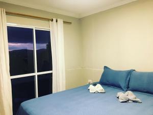 a bedroom with two towels on a bed with a window at Aconchego das flores in Campos do Jordão +12 photos