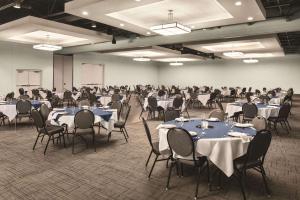 ein Zimmer mit Tischen und Stühlen mit in der Unterkunft Radisson Hotel and Conference Center Fond du Lac in Fond du Lac