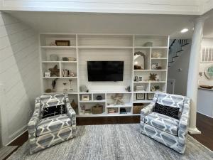 Una sala de estar con dos sillas y un televisor de pantalla plana. en Barefoot Children, en Southport