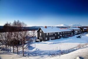 a large black building with snow on the ground at Vandrarhem Funäsdalen in Funäsdalen