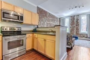 a kitchen with stainless steel appliances and a brick wall at E Bay St Loft by City Market and River Street in Savannah