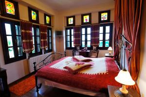 a bedroom with a bed with a red blanket and windows at Hotel Dryalos in Mileai