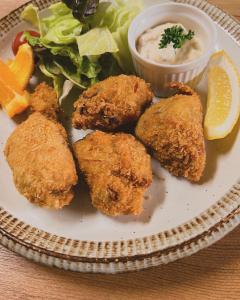 a plate of food with chicken tenders and salad and dipping sauce at irodori in Matsumoto