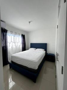ein Schlafzimmer mit einem großen Bett mit blauem Rahmen in der Unterkunft Cozy 2 Bedroom Apartment. in Santo Domingo