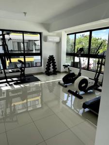 un gimnasio con cintas de correr y elípticas en una habitación con ventanas en Cozy 2 Bedroom Apartment., en Santo Domingo