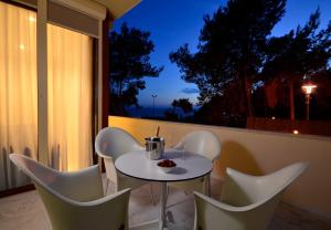- une table et des chaises blanches sur un balcon la nuit dans l'établissement Apartments with a swimming pool Podstrana, Split - 20098, à Podstrana