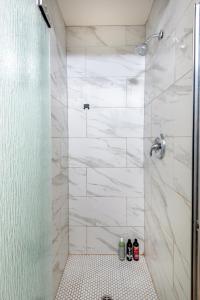 a bathroom with a shower with white marble tiles at Exquisite 1BR Suite ahead of Cedar-Sinai Hospital in Los Angeles
