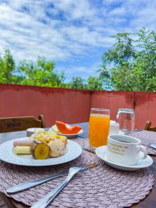 una mesa con un plato de comida y una taza de zumo de naranja en Pousada Sempre Viva Lençóis en Lençóis