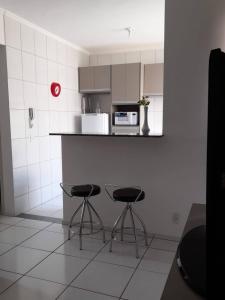 een keuken met 2 krukken en een aanrecht met een magnetron bij Apartamento Completo - Res Pq Humanita - Bl 02 in Uberlândia