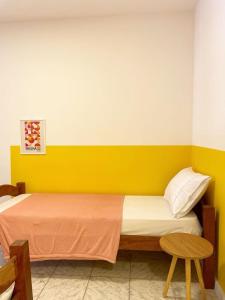 1 dormitorio con 1 cama con pared amarilla en Casa Aurora, en Salvador
