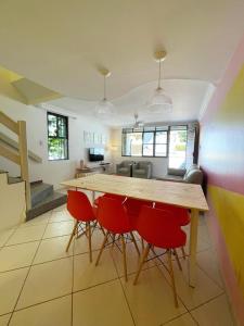 uma cozinha com uma mesa de madeira e cadeiras vermelhas em Casa Aurora em Salvador