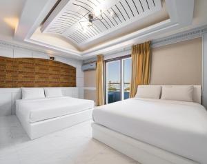 two white beds in a room with a ceiling at Sokcho Sinabro in Sokcho