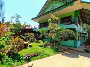 une maison verte avec un jardin en face de celle-ci dans l'établissement William Hearts Pension, à Puerto Princesa