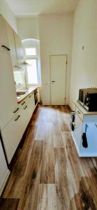 cocina con armarios blancos y suelo de madera en Cozy spacious room near Halle Hbf w/ iPad, Netflix & Wi-Fi, en Halle an der Saale