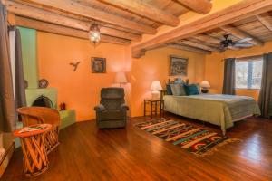 1 dormitorio con paredes de color naranja, 1 cama y 1 silla en Casa Benavides Inn, en Taos