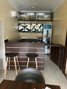 a bar in a restaurant with two stools and a refrigerator at Checkers Suite & Apartments in Abuja