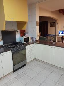 Una cocina con gabinetes blancos y un horno de estufa. en Un ambiente cómodo y placentero, en Guaymallén