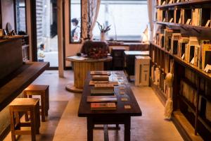Book & Guesthouse Hitotomaru في تويوكا: غرفة بها طاولات وكراسي في مكتبة