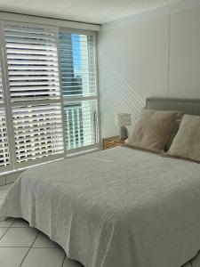 a bedroom with a large bed and two windows at Condor Surfers - Hosted by Coastal Letting Company in Gold Coast