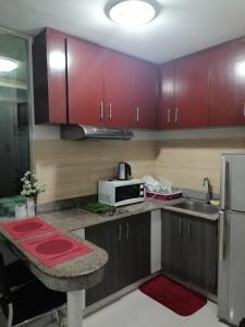 a kitchen with red cabinets and a microwave at Robinson manila birchtower in Manila