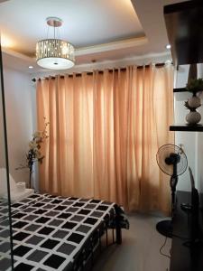 a bedroom with a large curtain and a chandelier at Robinson manila birchtower in Manila
