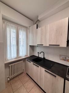 uma cozinha com armários de madeira, um lavatório e uma janela em Casa Bardolina - Baia Flaminia em Pesaro
