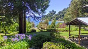 un jardín con banco, cenador y flores en Arrayanes en San Carlos de Bariloche