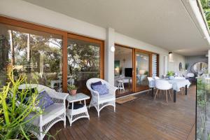 a patio with wicker chairs and tables on a deck at Cove Point in Noosa Heads