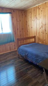 een slaapkamer met een bed in een houten kamer bij Acogedora Cabaña in Cartagena