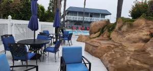 un patio con mesas y sillas azules y una piscina en The Grove at Pismo Beach en Pismo Beach