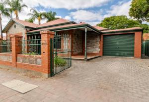 ein Backsteinhaus mit einem Tor und einer Garage in der Unterkunft Stylish Villa in Nailsworth By Host Solutions in Broadview