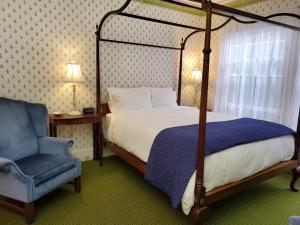 um quarto com uma cama de dossel e uma cadeira azul em Harbourside Inn em Northeast Harbor