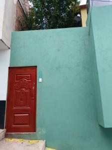 eine rote Tür an der Seite einer grünen Wand in der Unterkunft Casa Victoria in Cusco