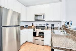 a kitchen with white cabinets and a stainless steel refrigerator at Upscale 3BR Near Disney - Pool and Hot Tub! in Orlando