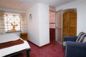 1 dormitorio con cama, ventana y silla en Aguaymanto pisac hostel, en Písac