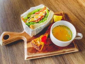 ein Sandwich und eine Tasse Suppe auf einem Holztablett in der Unterkunft UMEDAHOLIC HOTEL in Osaka