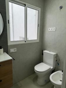 a bathroom with a toilet and a sink and a window at UIM Mediterraneo ATICO Cendoya Wifi in Puerto de Sagunto +9 photos