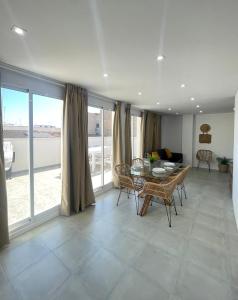 een woonkamer met een tafel, stoelen en ramen bij UIM Mediterraneo ATICO Cendoya Wifi in Puerto de Sagunto