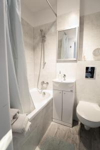 baño blanco con lavabo, bañera y aseo en PiotrApartments II, en Varsovia