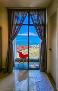 a room with a large window with a red chair at THE SHORE KOTA KINABALU - SABAKUBA HOMESTAY B13-13A in Kota Kinabalu