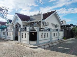 a white house with a balcony on a street at SAMAWA FAMILY House in Banyuwangi