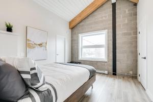 een slaapkamer met een bed en een bakstenen muur bij Complexe La Voûte in Laval