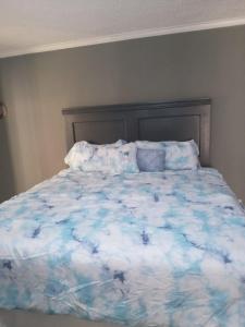 a bed with a blue and white comforter and pillows at Country Manor in Ocho Rios